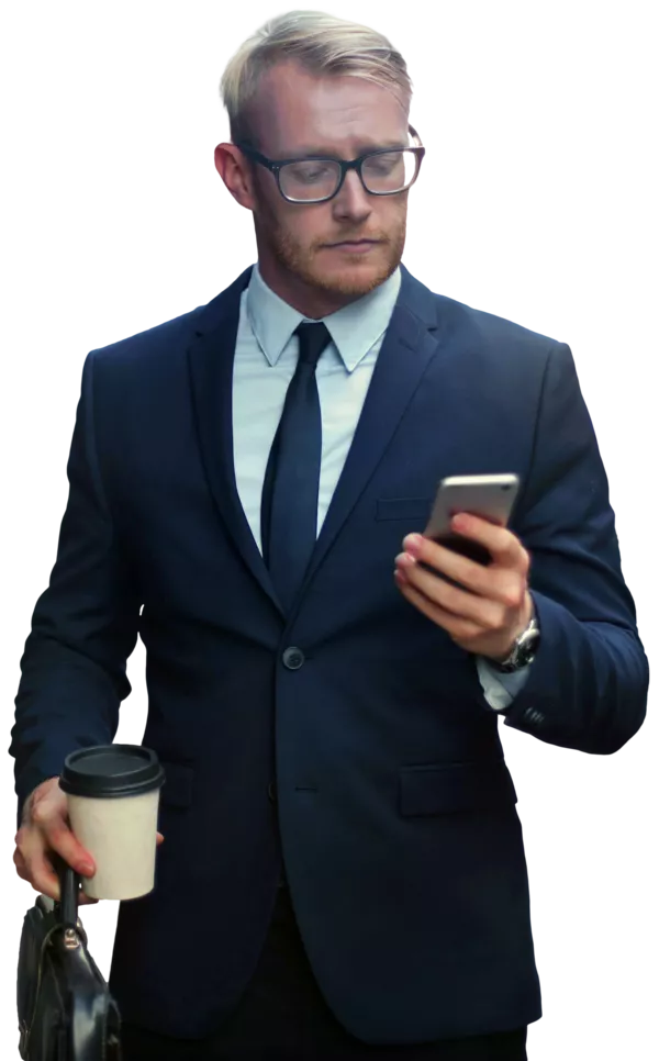 A business man holds a coffee and briefcase in one hand and looks at his phone in the other as he walks.