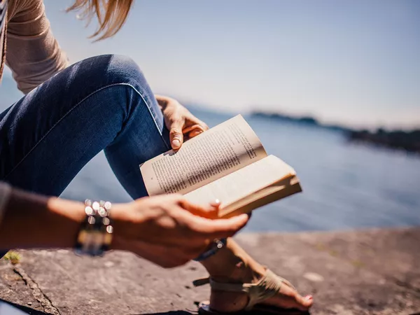 A woman reading a book on a beach.