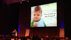 A humourous keynote slide from a DrupalCon. The slide shows a toddler clenching a fist and some wording saying 'Time to kick ass with Drupal 8'