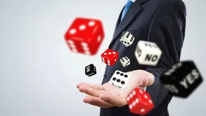 An ambiguous figure in a suit throwing dice towards he camera.