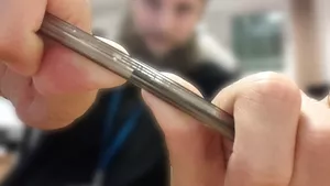 A man is holding a pen up to the camera and is in the process of snapping it in half.