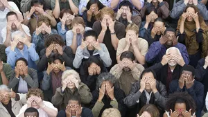 A crowd of people covering their eyes.